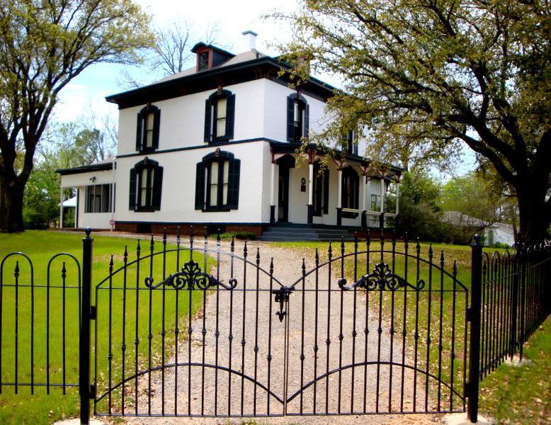 Photograph of white house surrounded by iron fence